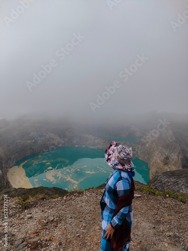 a woman who is pointing towards the beautiful lake kelimutu
