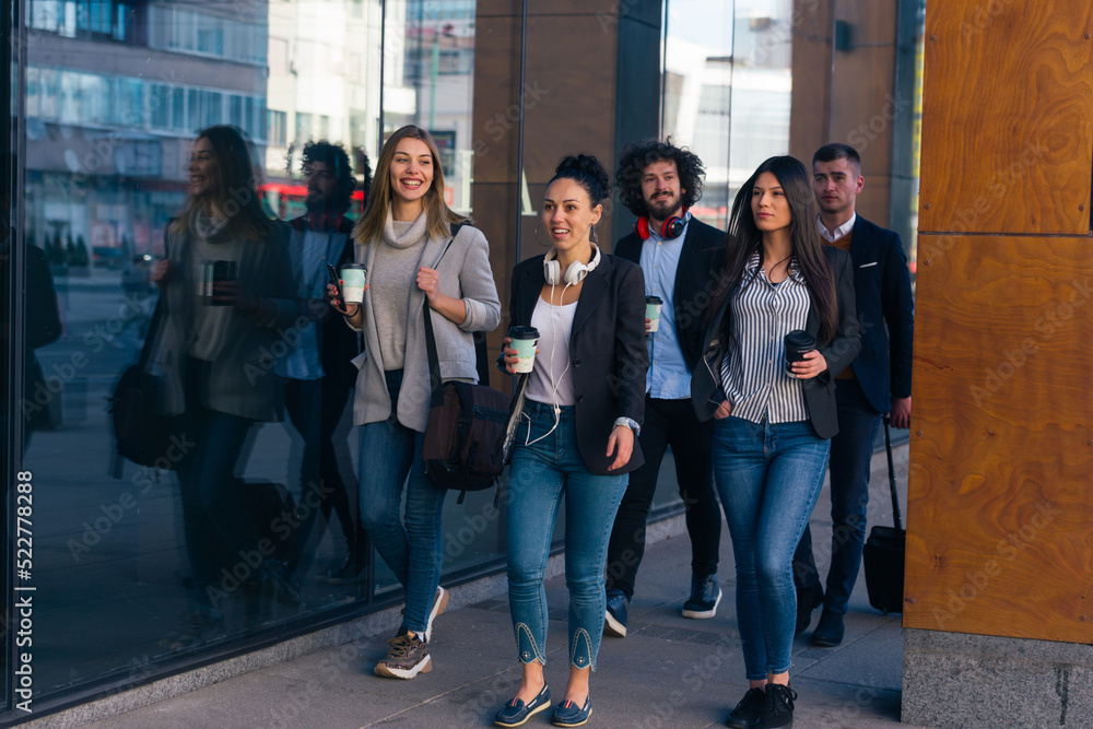 Obraz premium Full length of a group of colleagues in casual businesswear discussing business while walking at office hall.