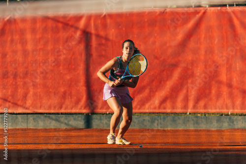 Caucasian woman in sportive outfit playing tennis on a clay court © qunica.com