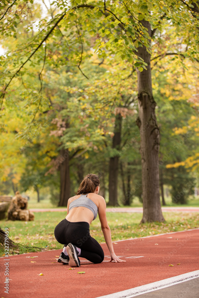 Preparing and focusing on the run and standing on the red track, in the park Preparing and focusing on the run and standing on the red track, in the park