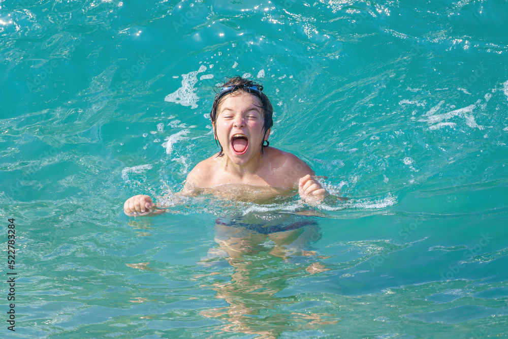 joyful boy bathes in sea waves on Cleopatra beach, Alanya, Antalya, Turkey