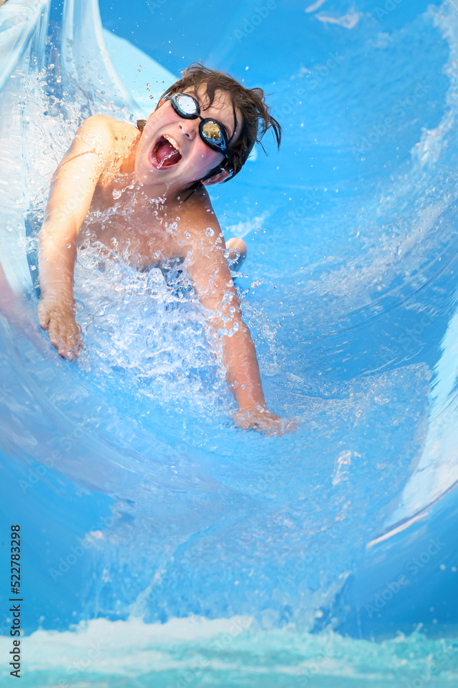 Fototapeta premium joyful boy going down the water slide in the water park, Alanya, Antalya, Turkey
