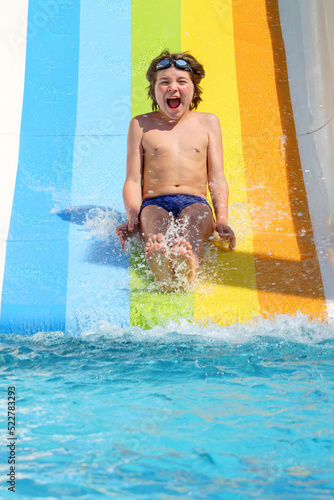 joyful boy going down the rainbow water slide in the water park, Alanya, Antalya, Turkey © Sergey Bogomyako