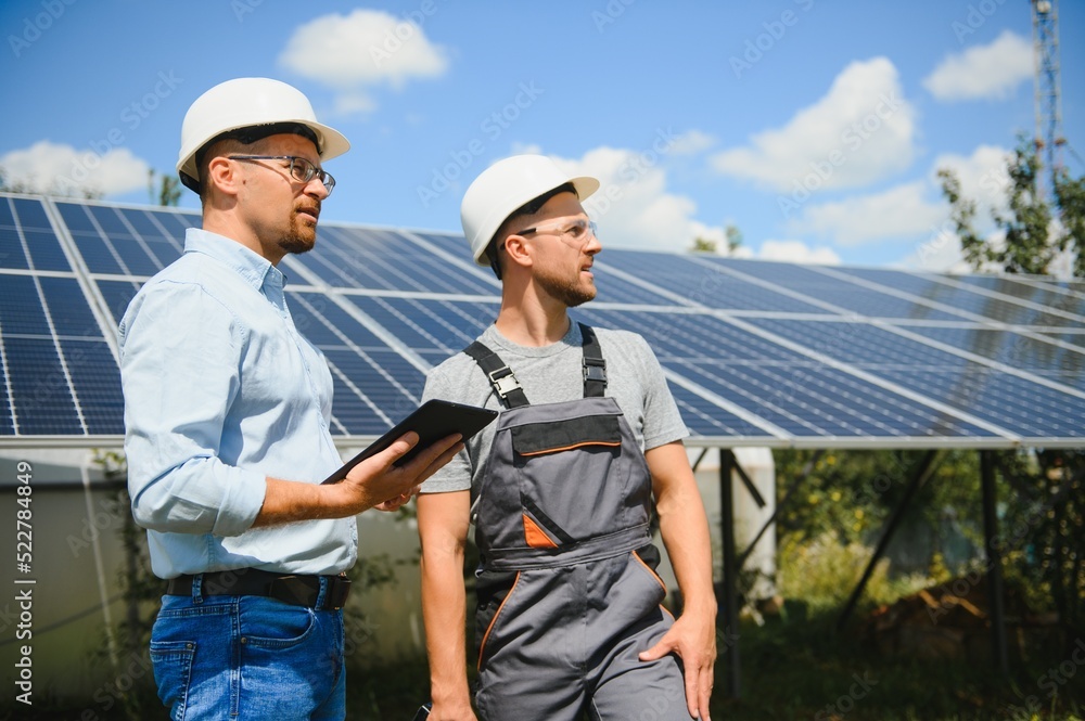 Two engineers are conducting outdoor inspection of solar photovoltaic panels