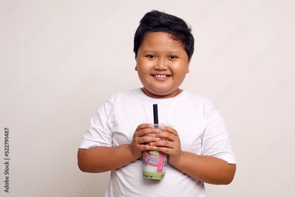 Happy asian boy standing while holding a drinking package. Isolated on white. Happy asian boy standing while holding a drinking package. Isolated on white.