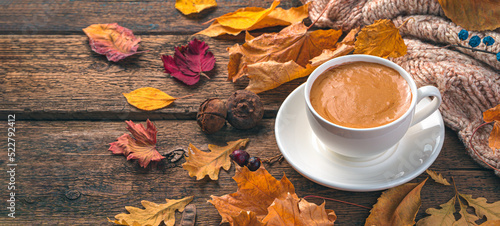 Coffee mug and autumn foliage on a wooden background. Cozy autumn composition. Side view, copy space