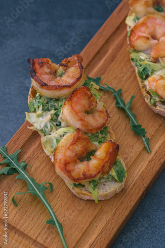 Fresh mediterranean bruschettas with grilled shrimps and salad greens.