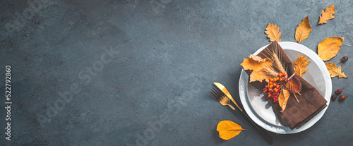 Autumn background with a plate with cutlery on a graphite background. The concept of Halloween, Thanksgiving. Top view, copy space