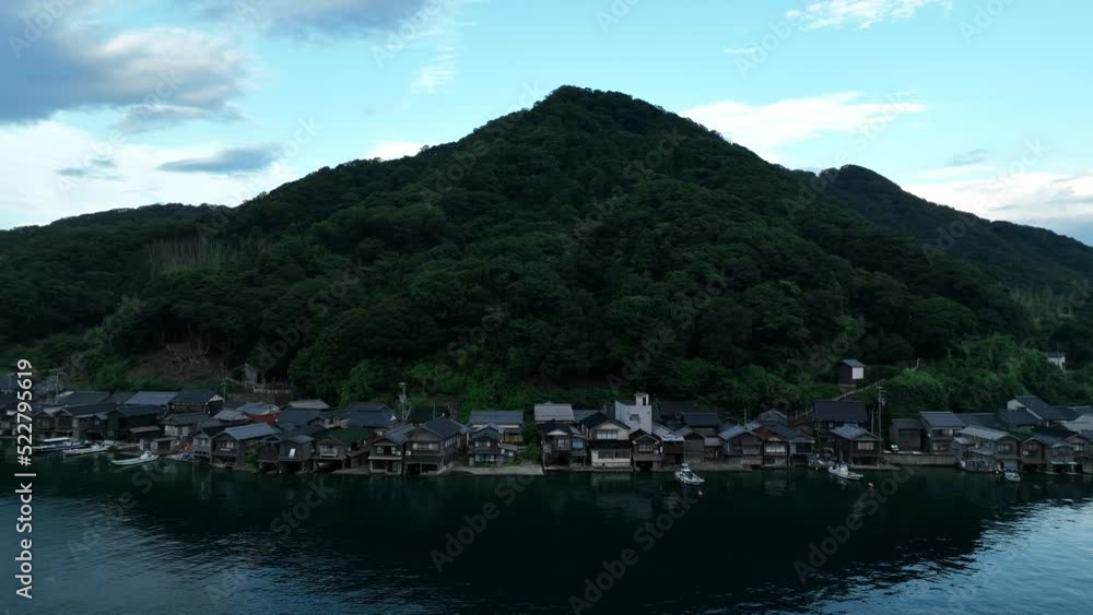 Rotate around row of houses in fishing village between water and mountain Rotate around row of houses in fishing village between water and mountain