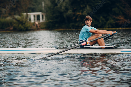 Sportsman athlete single scull man rower rowing technique on boat. Paddle oar splash movement