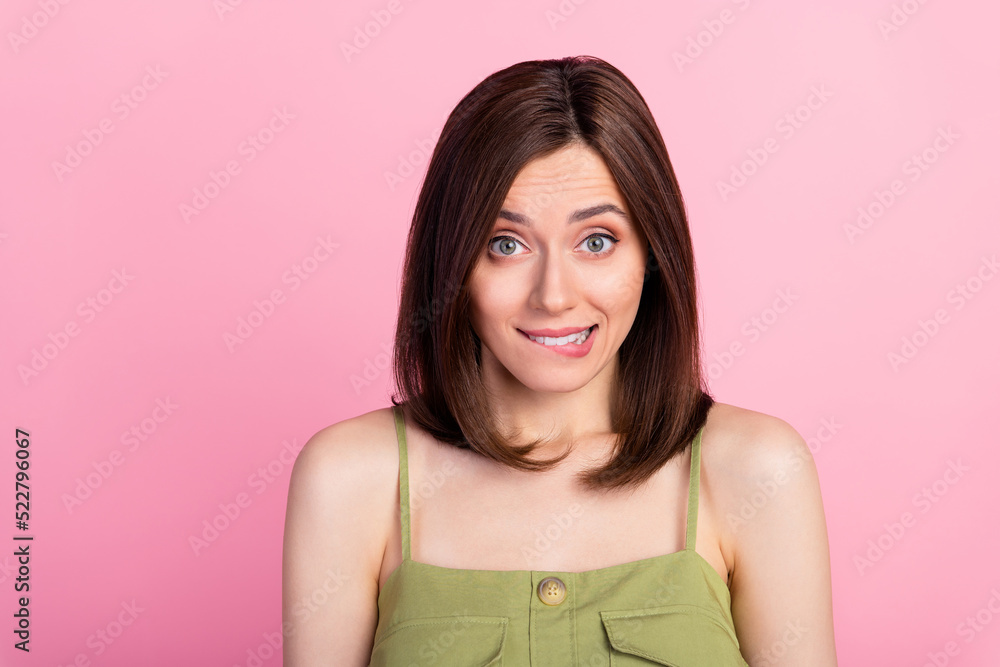 Photo of shy brunette lady bite lip wear khaki top isolated on pink color background Photo of shy brunette lady bite lip wear khaki top isolated on pink color background