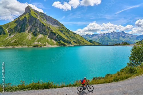 active senior woman, riding her electric mountain bike at Spuller Lake in the Arlberg area near the famous village of Lech, Tirol, Austrian Alps