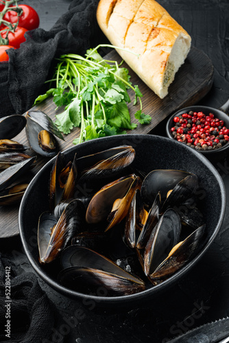 Boiled Mussels with parsley and spices and bread, in bowl, on black background