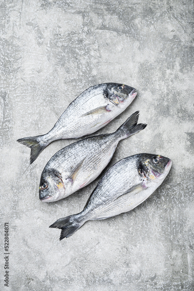 Whole dorado Sea bream fish with herbs for grill over textured grey background  top view space for text.