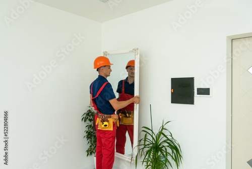 Furniture assembling. the repairman installs the mirror at living room of new house. photo