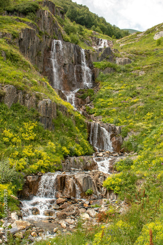 Small rocky waterfall surrounded by green forest in the Caucasus mountain range. Mestia-Ushguli trekking trail  Georgia. 