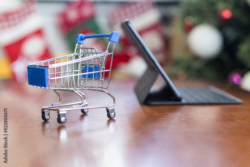 toy trolley and a Christmas tree on background. Copy space - concept of online shopping, ordering goods, home delivery, new year 2023, decoration, preparation