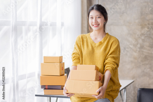 SME Online seller Young Asian woman freelance working at home with boxes, checking online order orders from customers delivery package shipping postal SME entrepreneur online business © David