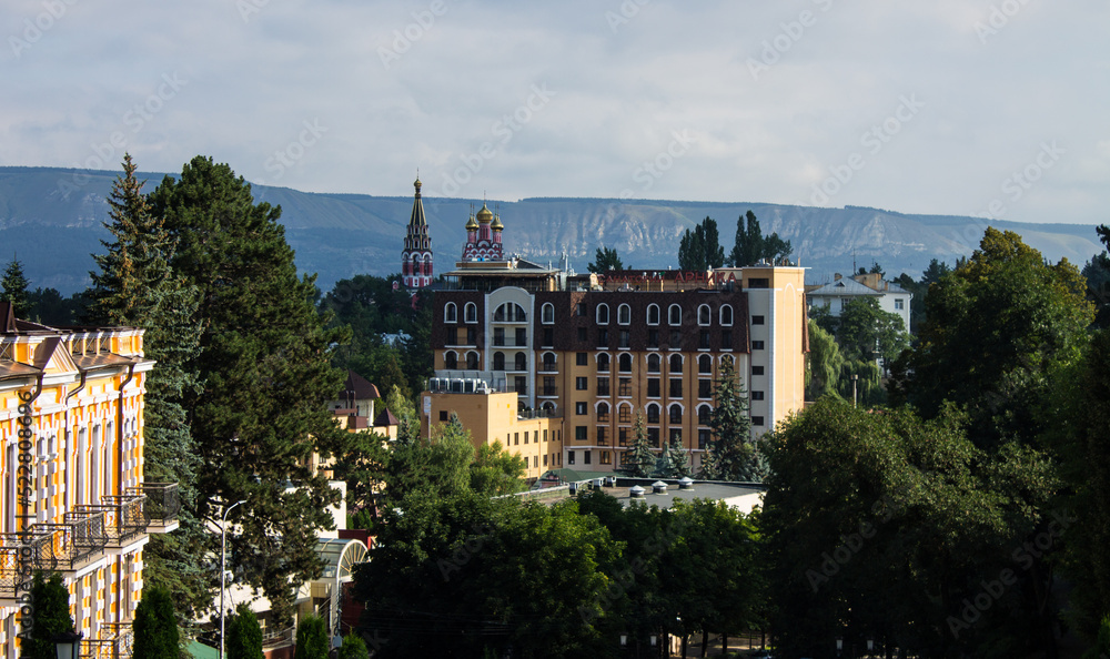 Fototapeta premium panoramic view of the historic city center with a church and buildings among green trees on a sunny summer day in kislovodsk