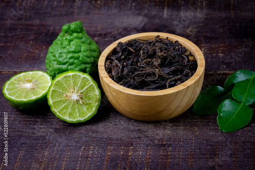 Bergamot tea or Earl Grey tea in wooden bowl and fresh bergamot fruit on rustic wooden background, top view.