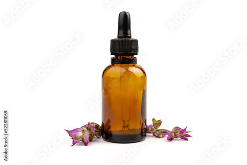 A bottle of essential oil with fresh blooming clary sage twigs on white background.