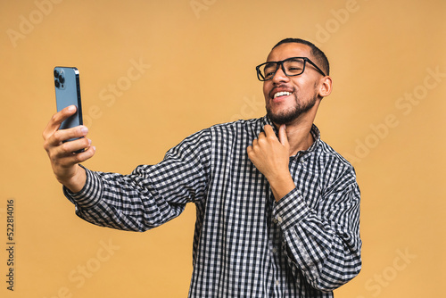 Portrait of handsome excited thinking serious african american black guy wearing casual sending and getting messages to his lover isolated over beige background. Using phone. © denis_vermenko