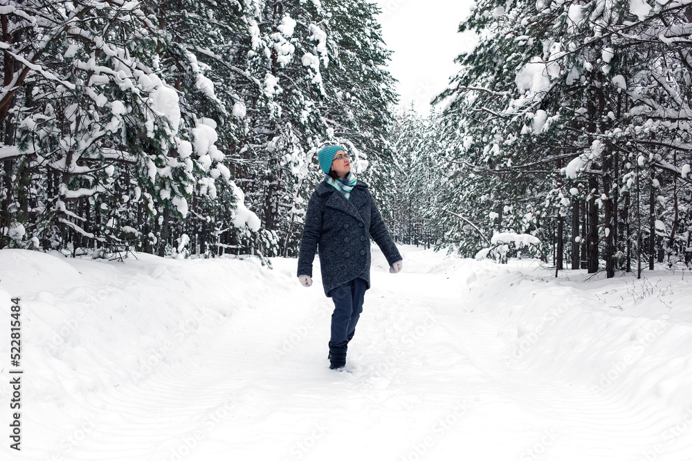 A woman is walking in the winter snowy forest.