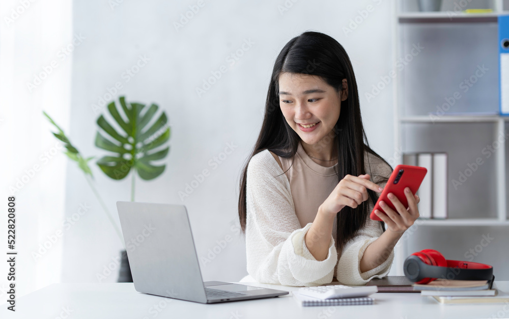 Asian businesswoman uses a mobile phone in her private office and smiles happily. Asian businesswoman uses a mobile phone in her private office and smiles happily.