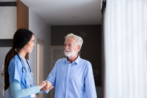 happy senior male patient health check and takecare by young female doctor or nurse at home after retirement for good health photo