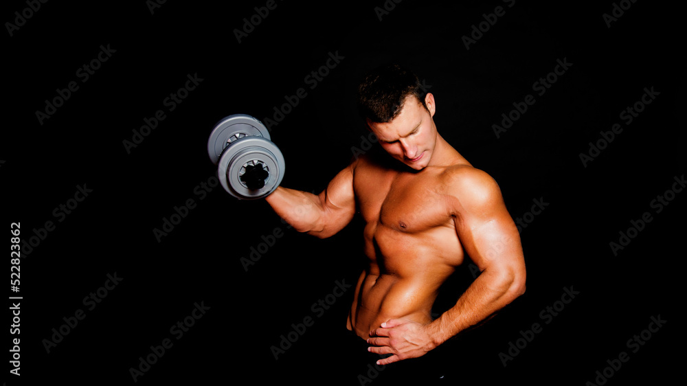 Young attractive sportsman with dumbbells. Male athletic body.	