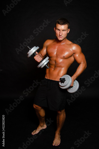 Young attractive sportsman with dumbbells. Male athletic body. 