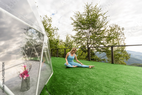 a woman is doing exercises on the terrace of a transparent bubble dome