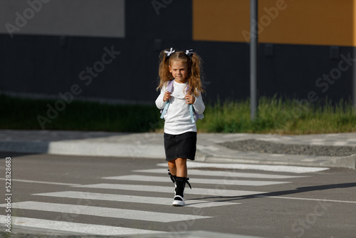 schoolgirl crosses the road at a pedestrian crossing 