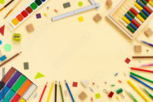 Set of school and office supplies. Multicolored paints, pencils, plasticine, buttons, scissors, rulers on paper beige background.