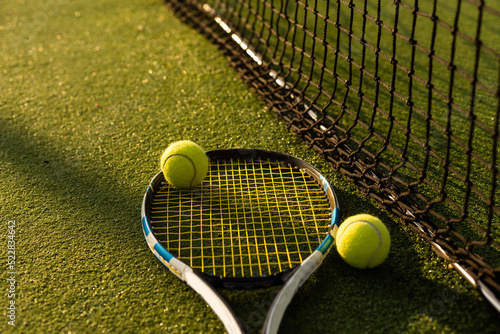 A tennis racket and new tennis ball on a freshly painted tennis court.