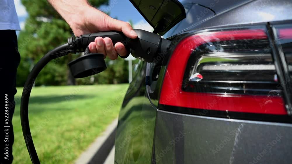 Caucasian man connect charger to electric car. Caucasian man connect charger to electric car.