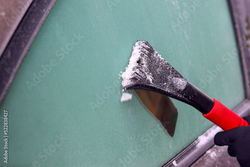 Photography Hands with a brush clean the car window from snow in winter