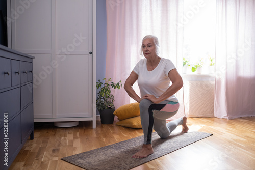 woman sitting on the yoga mat and stretching her legs in the living room. photo