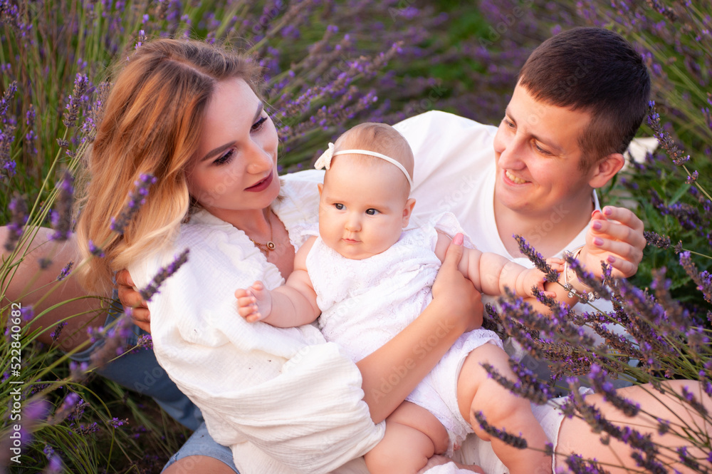Beautiful portrait of a young family with baby in lavender field. Family love and value concept. Beautiful portrait of a young family with baby in lavender field. Family love and value concept.