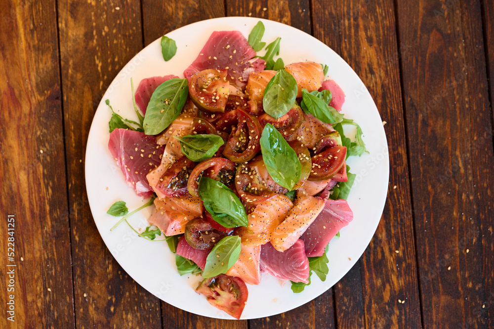 Healthy salad with raw salmon, tuna, green salad, tomato, basil and sesame seeds Healthy salad with raw salmon, tuna, green salad, tomato, basil and sesame seeds