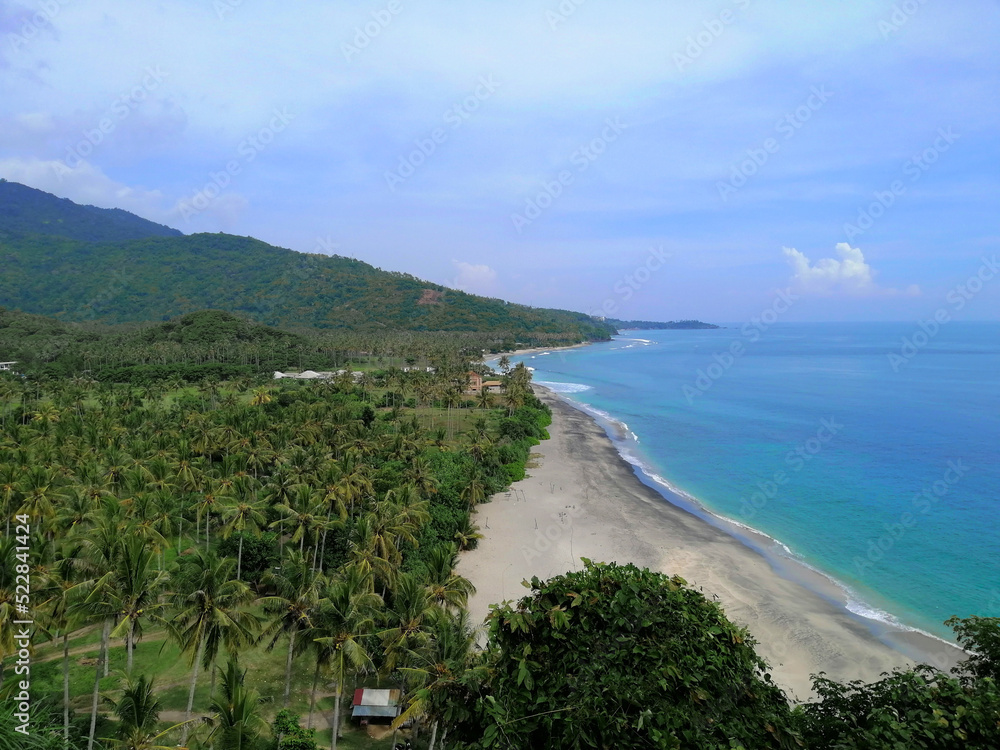 View of the sea from the Senggigi beach with coconut trees and mountain