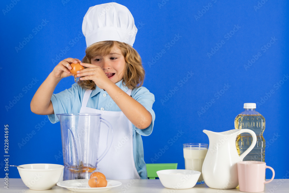 Child wearing cooker uniform and chef hat preparing vegetables on kitchen, studio portrait. Cooking, culinary and kids food concept. Child wearing cooker uniform and chef hat preparing vegetables on kitchen, studio portrait. Cooking, culinary and kids food concept.