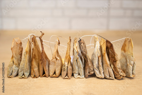 Used tea bags are stored in a row on a white and wooden background. Tea bags for reuse. Recycling is about ecology. Used tea bags for re-using as a compress, to acidify oil, to revitalize puffy eyes photo