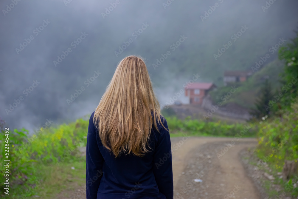 Girl walking alone on mountain highway in Spring foggy day. Girl walking alone on mountain highway in Spring foggy day.