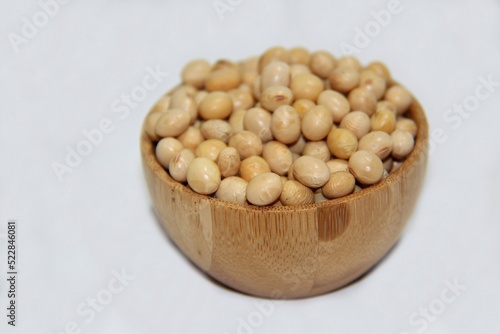 Soybeans (Glycine max) in a wooden bowl isolated on white background.