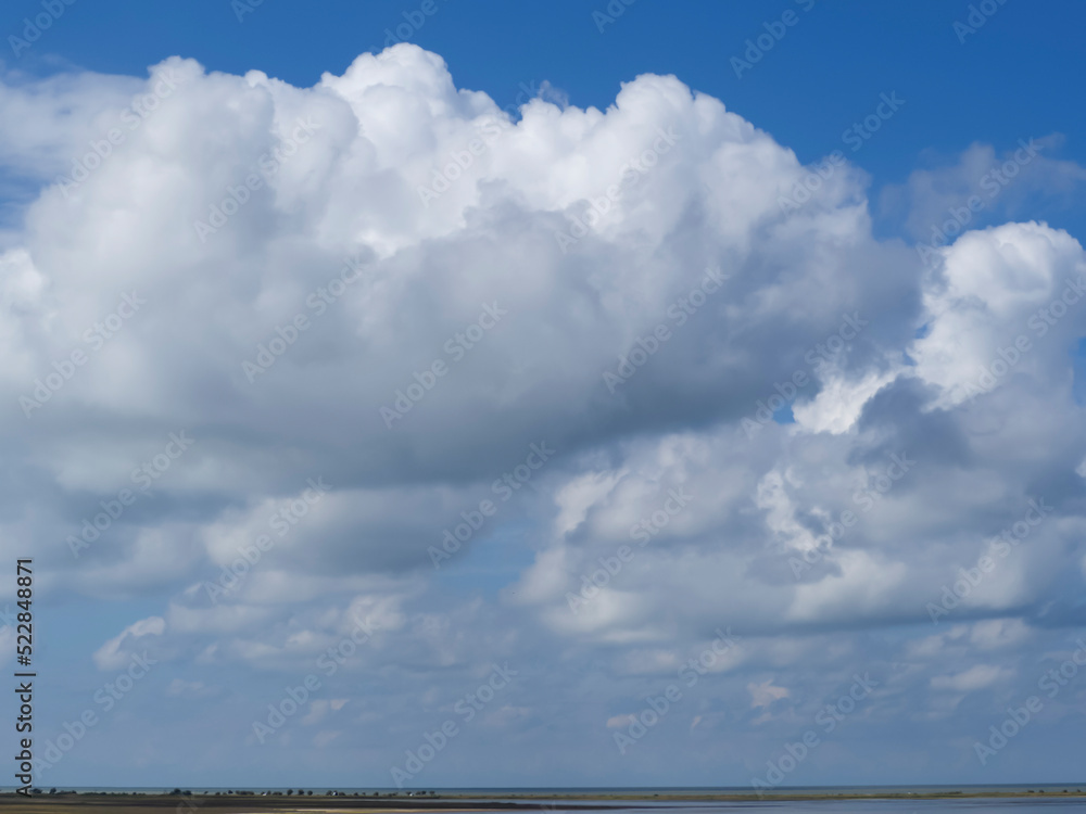 Huge cumulus clouds over the horizon. Clouds in a blue sky, natural texture. Blue sky background with lots of clouds Huge cumulus clouds over the horizon. Clouds in a blue sky, natural texture. Blue sky background with lots of clouds