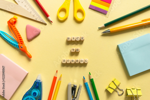 Back to school background. School accessories on a yellow background. Wooden blocks with letters photo