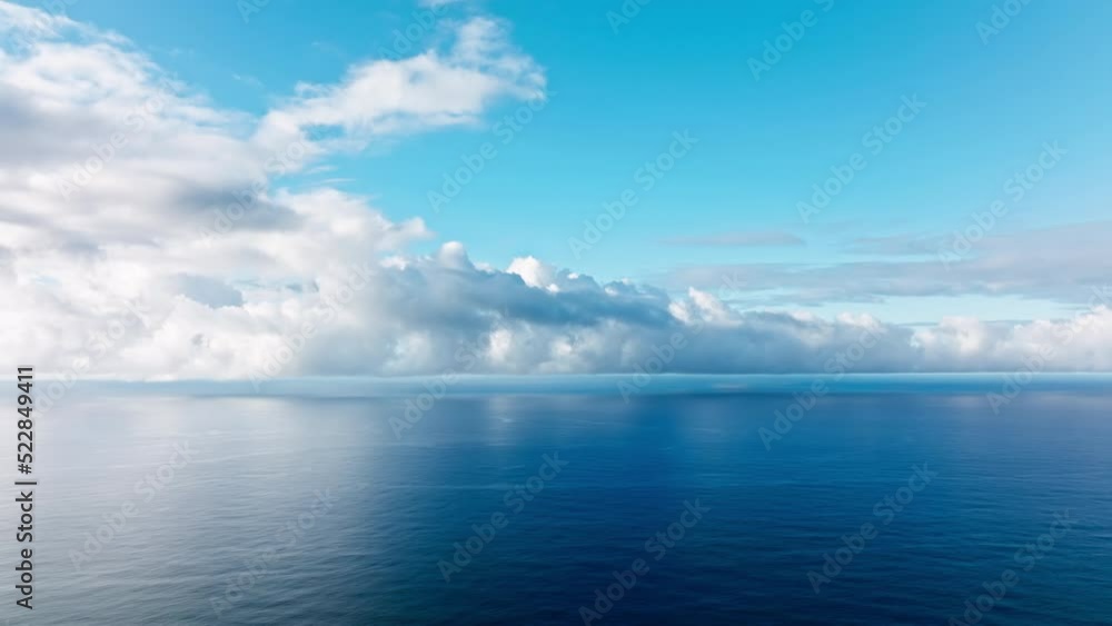 Epic flight over perfect deep blue sea with scenic white clouds in blue sky. Endless horizon seen in distance, cinematic blue depths of perfect calm ocean. Beautiful calm sea, evening sky background Epic flight over perfect deep blue sea with scenic white clouds in blue sky. Endless horizon seen in distance, cinematic blue depths of perfect calm ocean. Beautiful calm sea, evening sky background