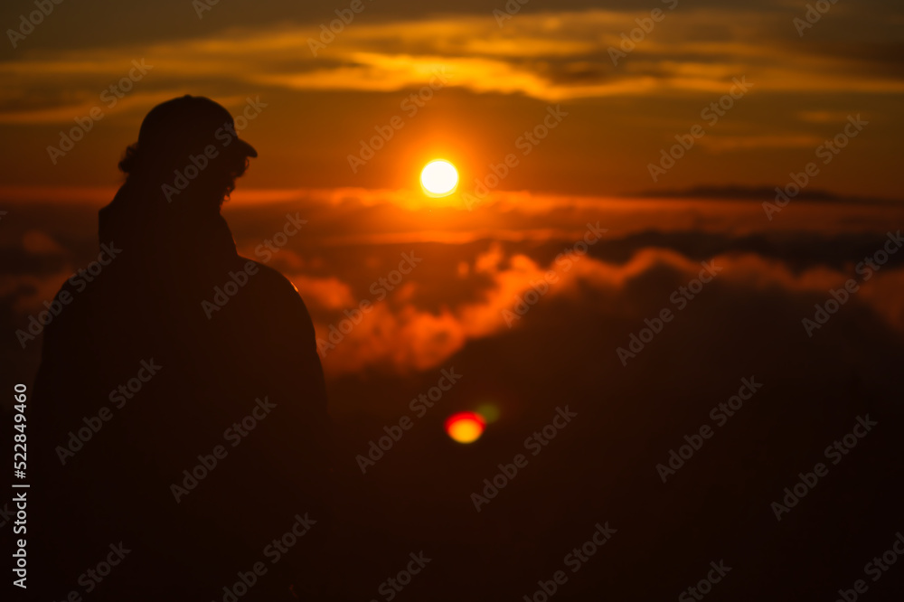 Man looking to the sunset over the clouds