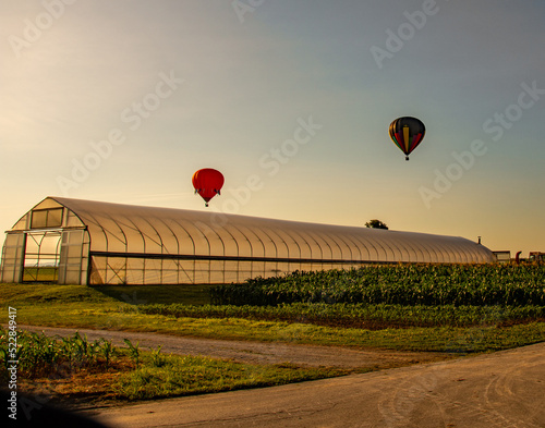 Hot air balloons fly over a green house in the early summer hours in Lancaster County, PA 